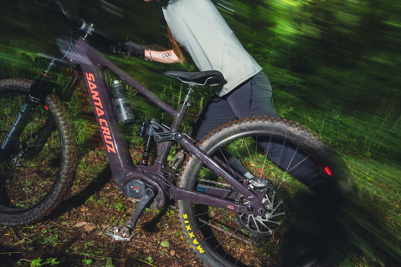 Ciclista pedaleando con Santa Cruz Vala AL en terreno montañoso, demostrando las capacidades dinámicas y de rendimiento de la e-MTB en condiciones reales de uso